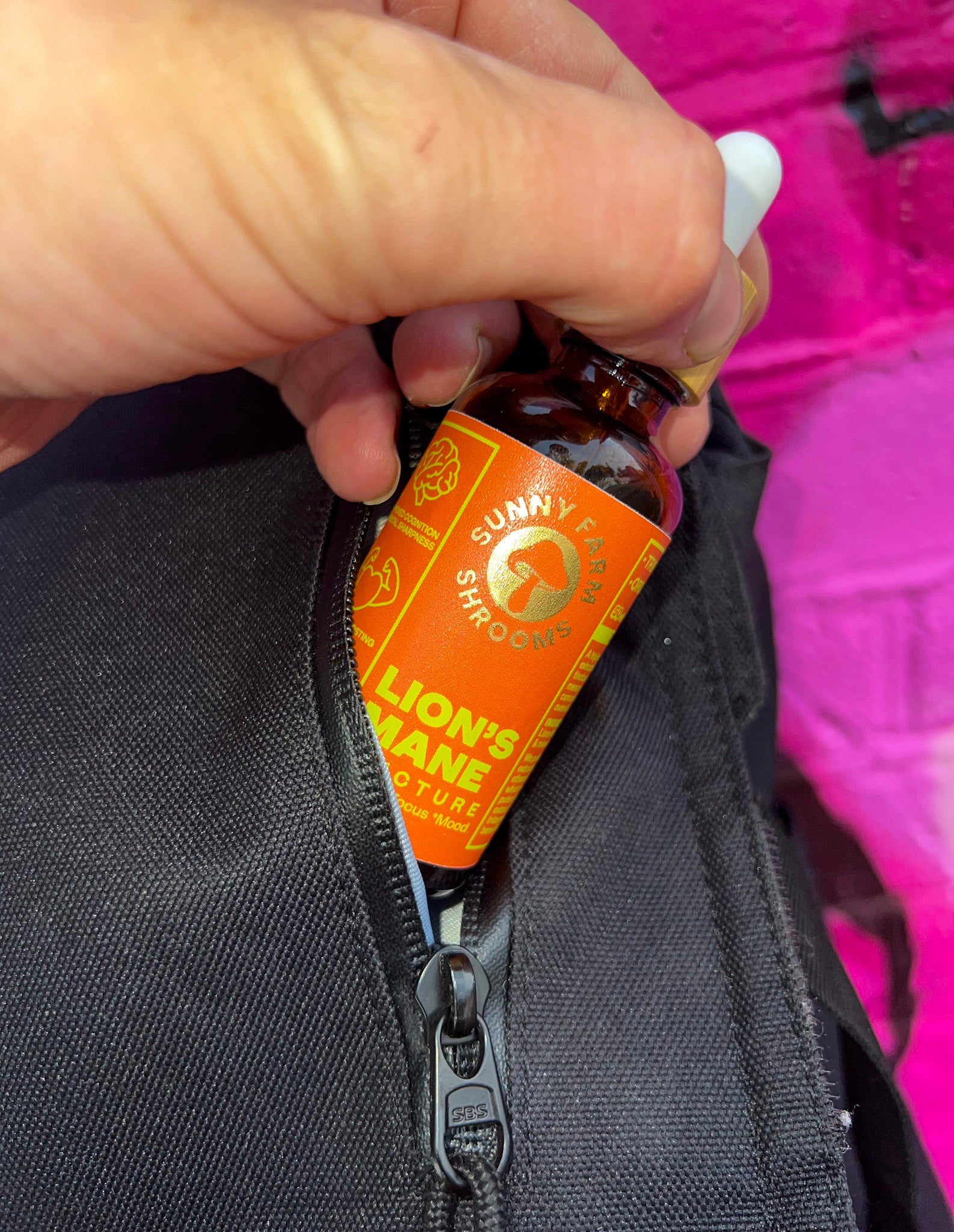 A bottle of lion's mane inside the pocket of a black backpack